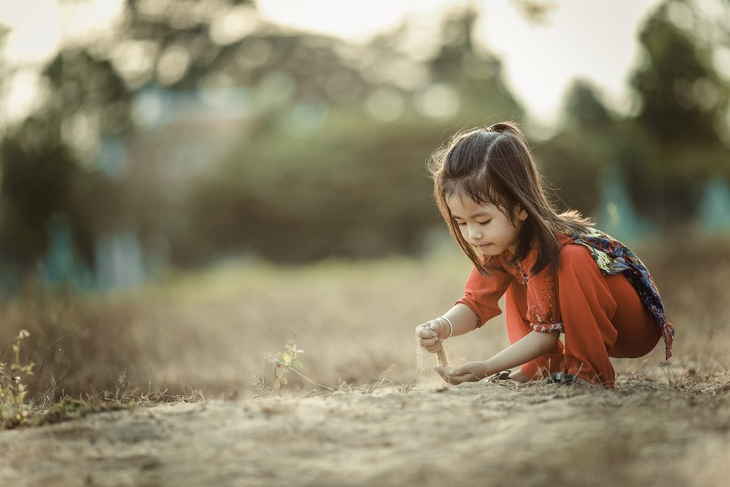 child experimenting with the feeling of sand